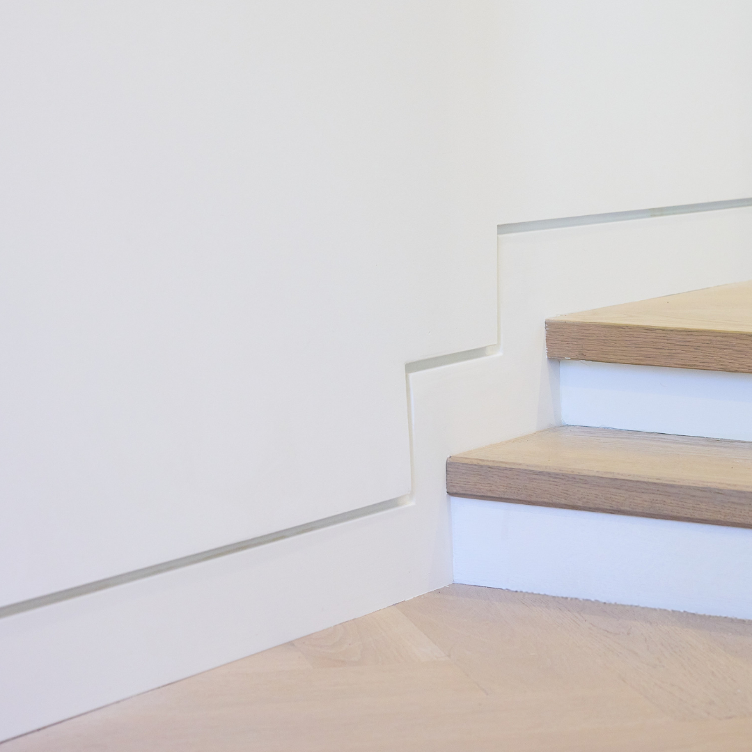 Shadow-line reveal detail where a recessed baseboard meets the drywall